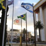 Entenda o que é ser parte do Povo de Deus. Imagem com um templo bonito ao fundo e as bandeiras da Jamaica, Israel, Brasil e da Igreja Universal ao fundo tremulando.