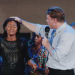 Jovem é curada de tumores nos seios durante cruzada evangelística da CfaN na Nigéria e testemunha milagre após oração de fé. Foto: Reprodução/YouTube/CfaN Europe