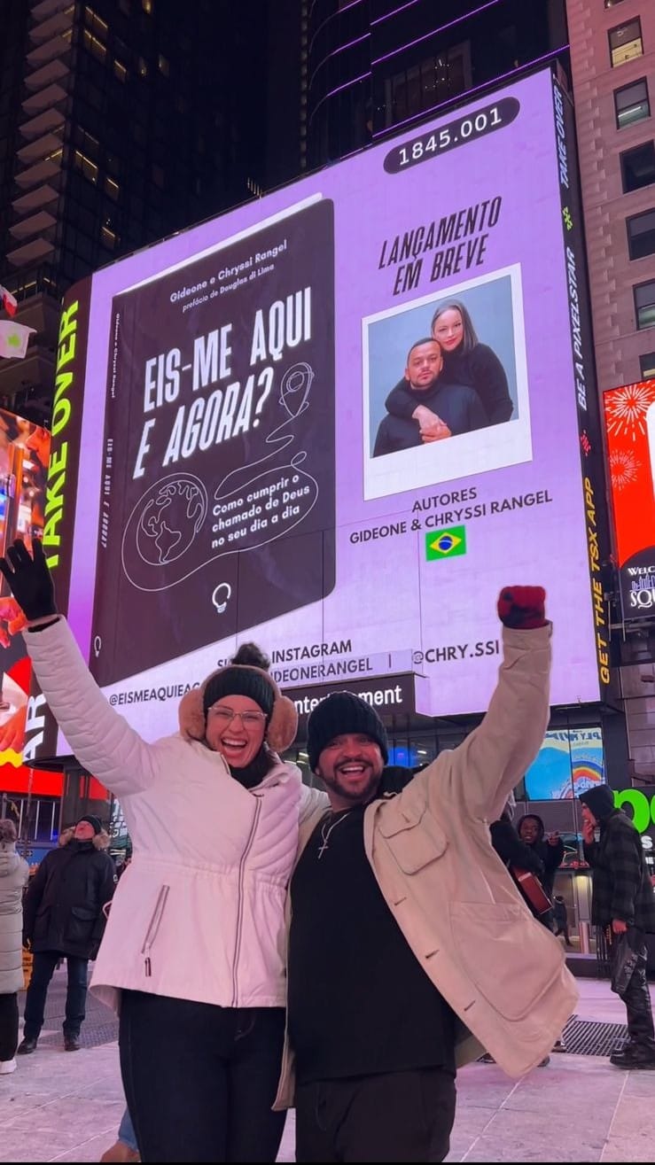 Casal revela capa do livro de estreia, "Eis-me aqui e agora?'', nos letreiros luminosos da Times Square, em Nova York. Foto: Arquivo Pessoal.