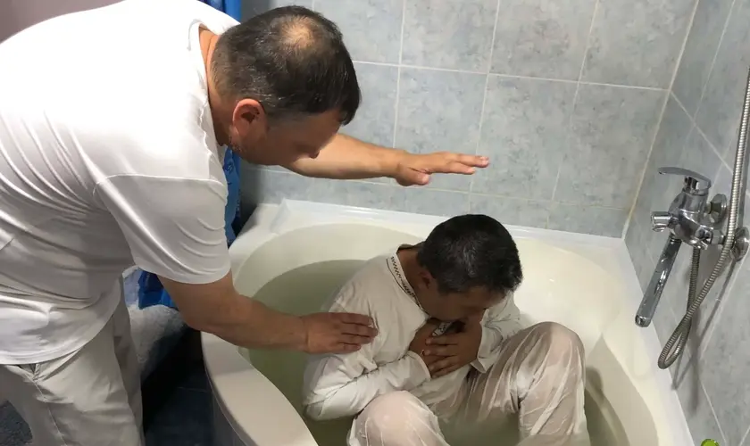 Um policial da Ásia Central, identificado como Roeslan*, tem batismo em banheiro de uma casa, temendo a perseguição por sua fé. Foto: Portas Abertas