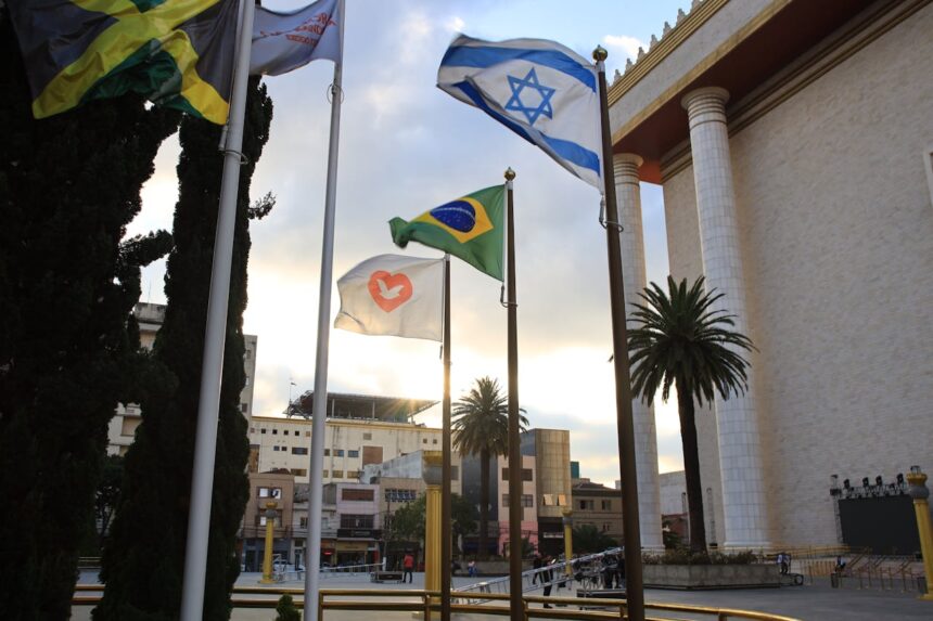 Entenda o que é ser parte do Povo de Deus. Imagem com um templo bonito ao fundo e as bandeiras da Jamaica, Israel, Brasil e da Igreja Universal ao fundo tremulando.