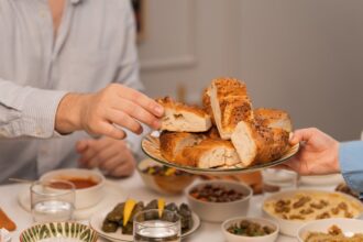 O que realmente te satisfaz? Uma imagem de um banquete com mãos de um homem e uma mulher pegando muitas comidas gostosas para comer.